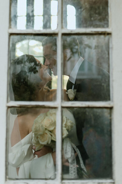 bride and groom kissing through window