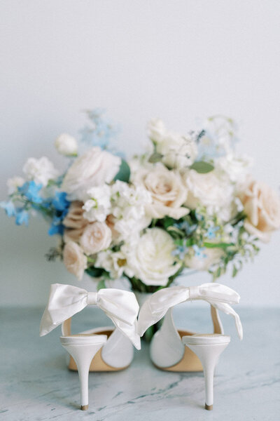 White bridal heels with bow and pastel flower arrangement, captured by Toronto photographer