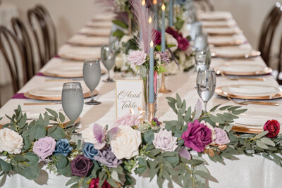 Chic wedding reception head table featuring lush floral arrangements and fine tableware for a luxury event.