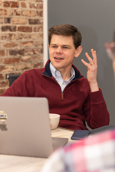 man in front of his computer holding a cup of coffee and talking to someone during a meeting Atlanta Brand Photographer