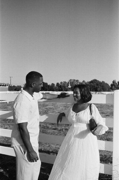 Girl leaning on a fence and guy leaning towards her, taken on black and white 35mm film.
