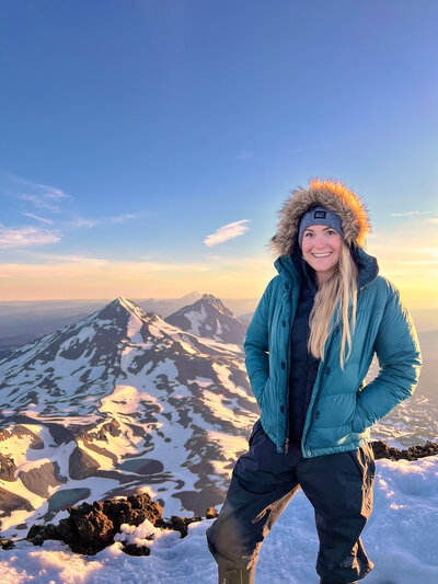 A woman stands on the summit of South Sister overlooking north and middle sisters