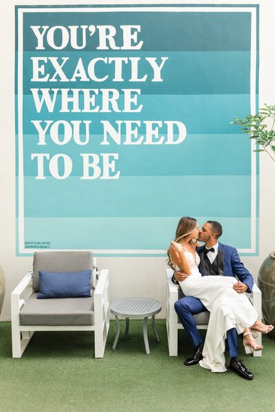 Bride and Groom sitting in a chair in front of large mural at Hotel Valley Ho.