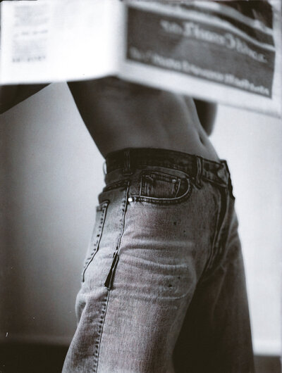 Black-and-white editorial-style photo of woman in jeans holding newspaper, symbolizing thoughtful social media strategy and brand audits