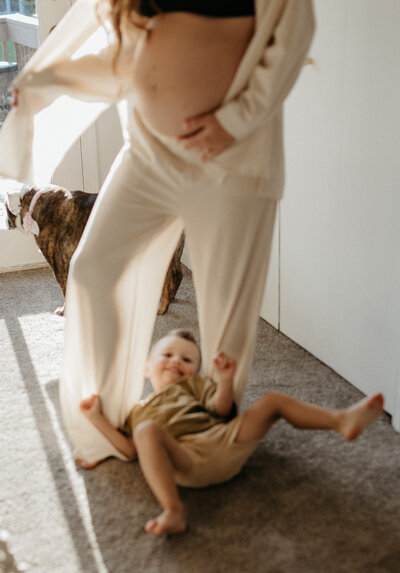 Child lays on the ground next to his mom and dog.