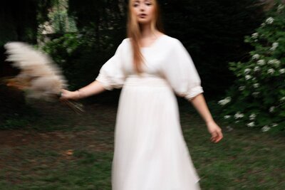 Portrait en flou artistique d'une jeune femme en robe blanche portrant un bouquet de fleurs pendant une séance photo portrait à Fontaine-sur-Saône
