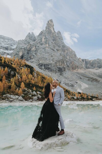 A couple snuggles on a stone at Lake Sorapis during their Dolomtites elopement