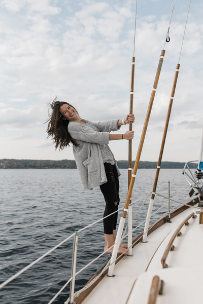 woman standing on edge of sail boat smiling