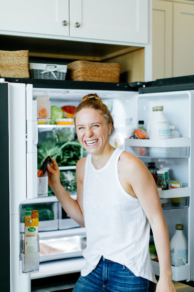 woman standing in front of refrigerator smiling
