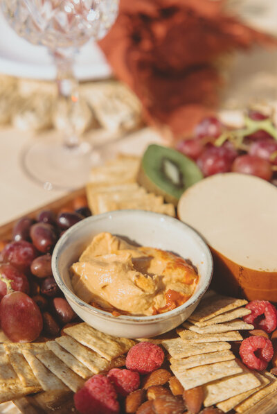 Let's Picnic Co. - Colorful snack tray with crackers, hummus, grapes, olives, raspberries, kiwi, almonds and cheese