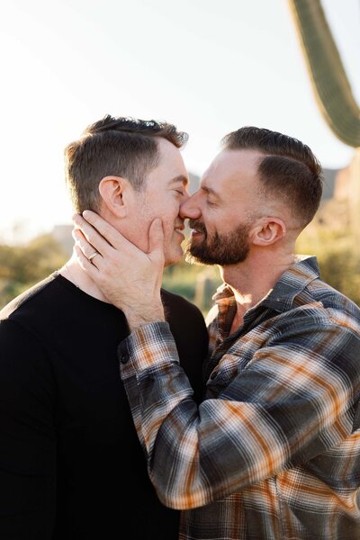 Two men hug and almost kiss in the desert for sunset photos