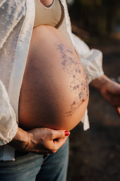 Babybauch mit Schatten einer Pflanze im Sonnenlicht