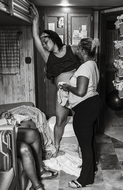 Tifton, GA birth photography: Powerful image of laboring woman, belly exposed as her midwife listens to baby heartbeat