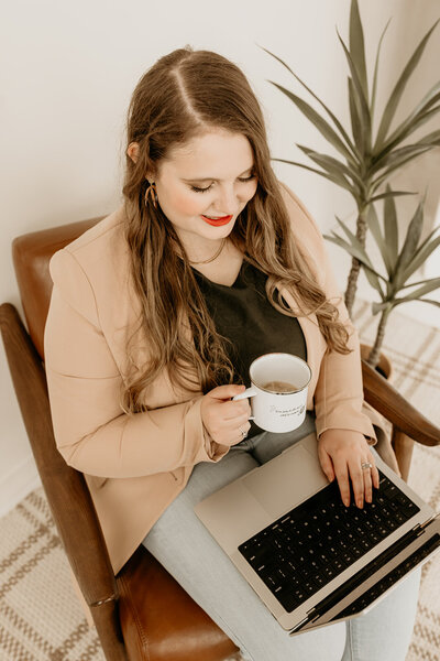 Emily Foster, a website designer and brand designer for wedding pros, looking at a laptop