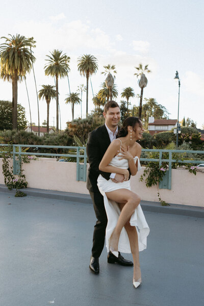 Beverly Hills Engagement Session. Couple in cocktail attire laughing while holding eachother from behind
