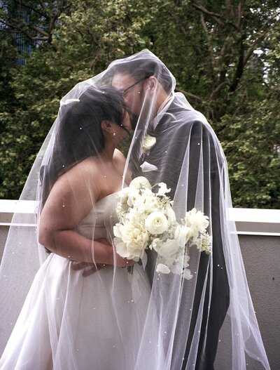 couple kissing underneath veil