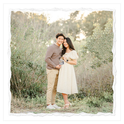 The picture depicts a serene and picturesque scene of a pregnant mother and her husband standing in a lush green field, with a backdrop of a forest and a stunning sunset. The mother is wearing a beautiful beige dress that accentuates her growing baby bump, while the father is dressed in a beige sweater and khakis, creating a harmonious and coordinated look.  The couple is holding an ultrasound image of their unborn child, a tangible representation of the new life they are about to welcome into the world. The setting is idyllic, with the verdant field and the warm hues of the sunset creating a sense of tranquility and joy.  The expressions on the couple's faces convey a mix of excitement, anticipation, and pure love as they gaze at the ultrasound image, no doubt filled with a sense of wonder and gratitude for the miracle they are about to experience.  The attention to detail in the image is remarkable, from the delicate folds of the mother's dress to the gentle breeze that seems to be caressing the couple's faces. The overall composition is well-balanced, with the couple positioned in the center, drawing the viewer's eye to the focal point of the image.  This picture is a beautiful and heartwarming representation of the joy and wonder of pregnancy, capturing a moment of pure bliss and celebration as the couple prepares to embark on the next chapter of their lives.