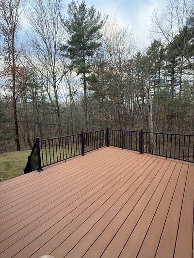 A pool deck with brown composite built around an above ground pool with a tan house
