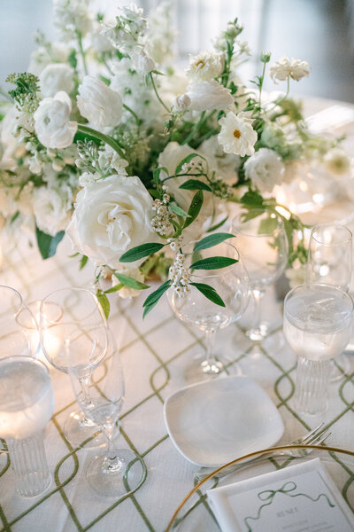 All white floral arrangement for an NYC wedding with roses, ranunculus and greenery