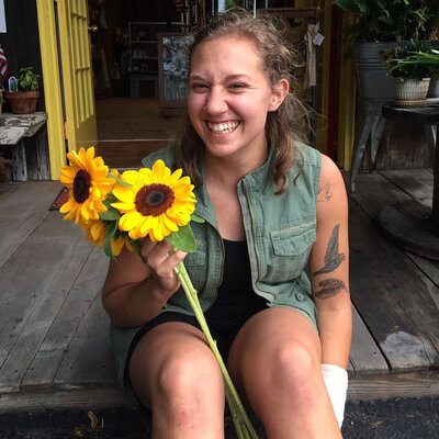Pittsburgh wedding florist Heavenly Blooms holding two sunflower stems while sitting on porch