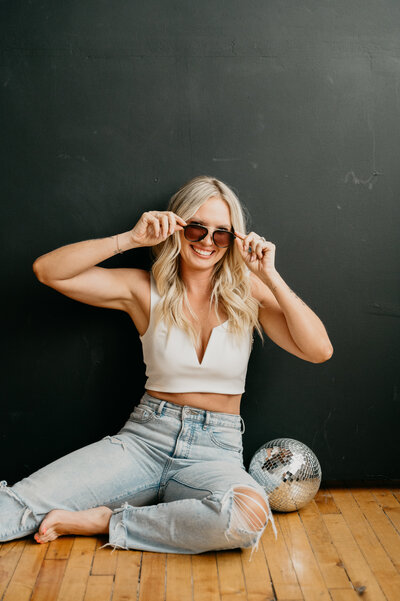 Woman in ripped jeans sits on a low bench
