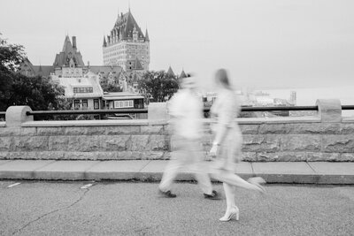 black and white portrait of a couple walking with the chateau frontenac in the background
