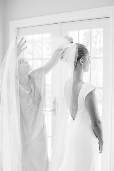 black and white photo of bride having veil placed in hair