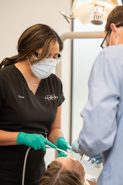 Dentist poses for a branding photo while working on a client's teeth