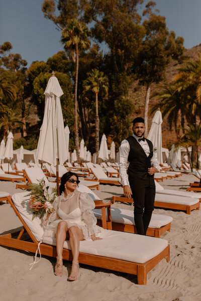 bride and groom posing on beach chairs