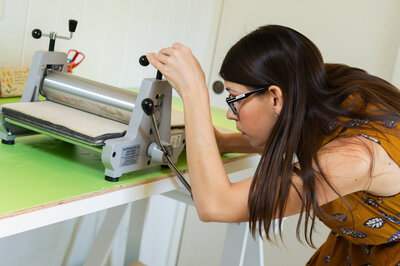 Woman with brown hair and glasses working on her stamp press.
