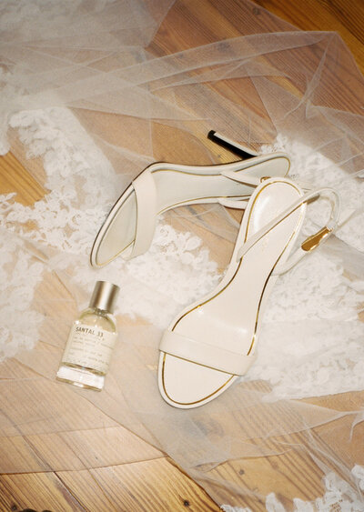 Brides wedding shoes on her veil with a bottle of perfume 