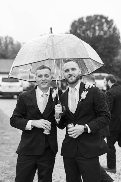 groom and best man under an umbrella