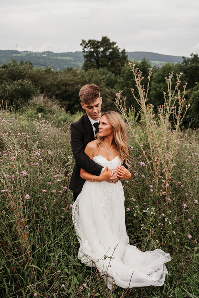 couple holding onto each other looking in the field at best view barn