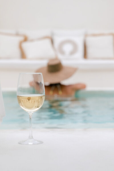 Woman lounging in a pool next to a glass of wine