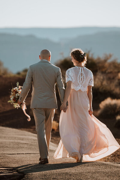 bride and groom walking down a road in the desert