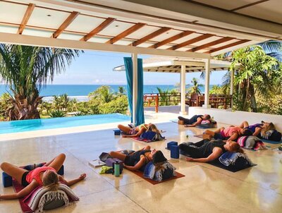 Students in restorative pose on the yoga deck in costa rica