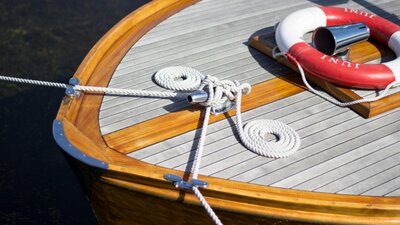 Bow of a wooden boat with rope and a lifebuoy on it