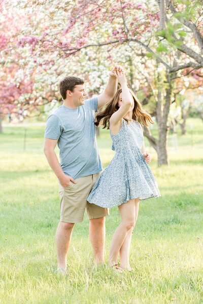 An engaged couple dancing in an apple orchard at Springtime