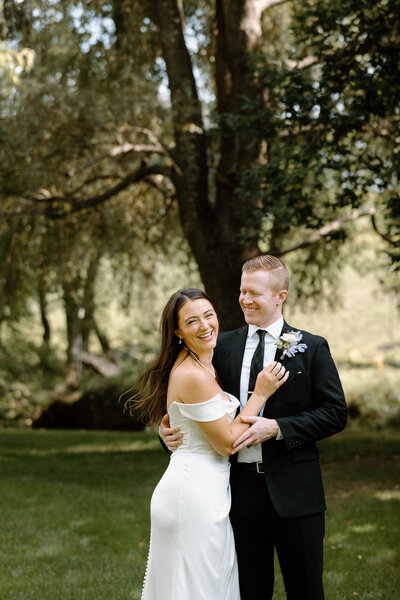The bride and groom smiling happily as they posed for their backyard wedding