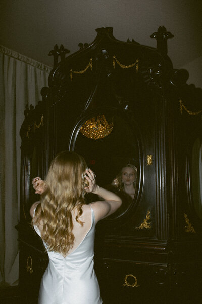 Bride standing by window with fairytale florals and pearl earrings.