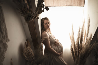 Portrait féminin naturel - séance photo grossesse, femme enceinte devant une fenêtre, tenant son ventre 