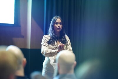 Trang Nova who is a speaking coach giving a talk in front of a crowd.