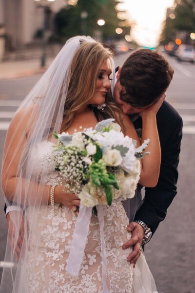 Destination wedding photography by Britt Elizabeth captures a heartwarming image of a bride and groom kissing on the street.