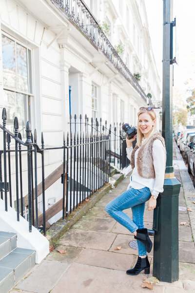 Philippa leaning on a lampost with her camera during a portrait shoot in London