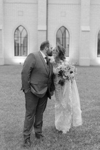 Catholic bride and groom kiss outside St. phillip the Apostle in Flower Mound, TX after their wedding mass.