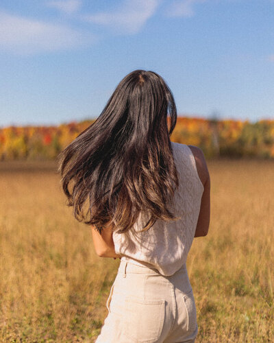 A woman walking in an open field. Representing a person who could boost their confidence with therapy for self-esteem in Manhattan. A confidence counselor in New York can help you set realistic self-esteem goals. So you can live a life you love!