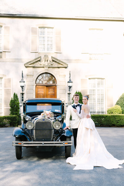bride and groom smiling in front of an antique car during their glen manor house portsmouth rhode island wedding