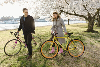 couple walks their bikes under the cherry blossoms in washington d.c.