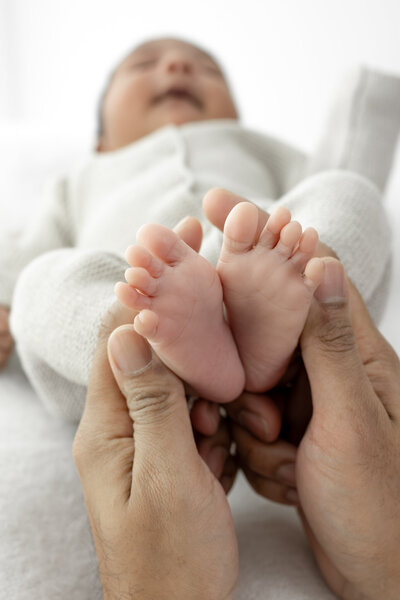 Lifestyle newborn photography session with dad holding baby's toes — captured by Alliston and Barrie maternity, newborn, and family photographer.