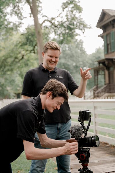 Storyteller team members smile as they set up a camera in an outdoor residential scene.